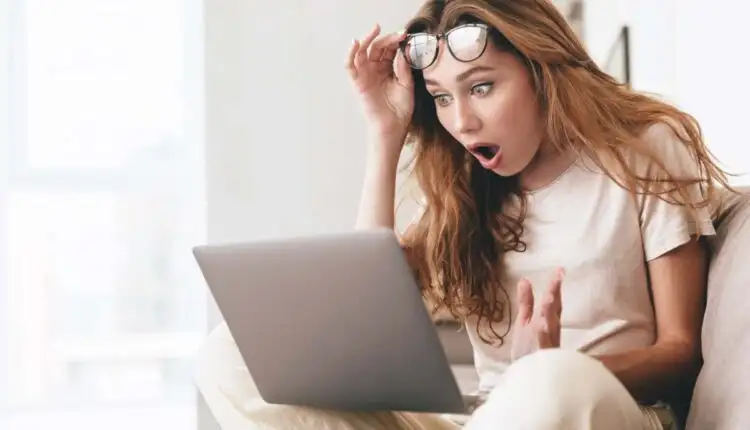 woman looking shocked at what she is seeing on her computer